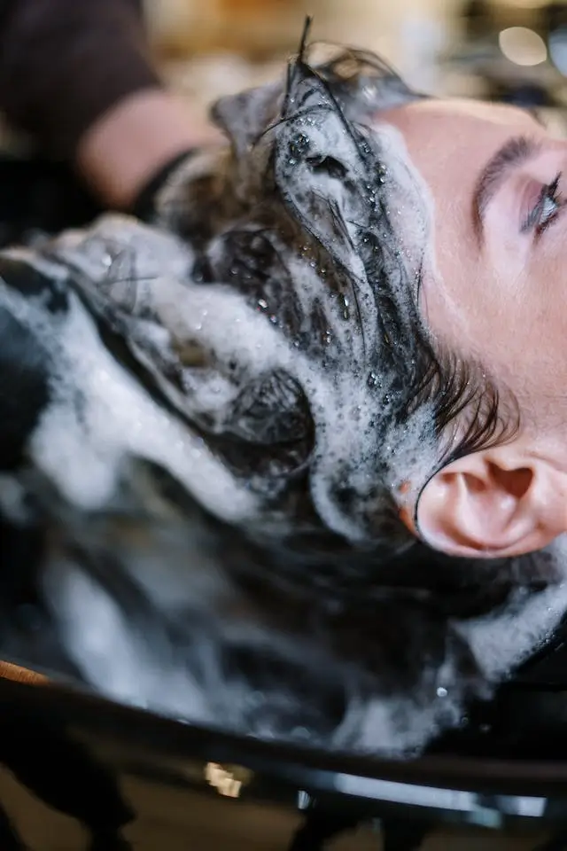 Stylist performing a relaxing scalp massage and hair wash on a male client